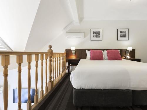 a bedroom with a large bed and a staircase at Mercure Canberra in Canberra
