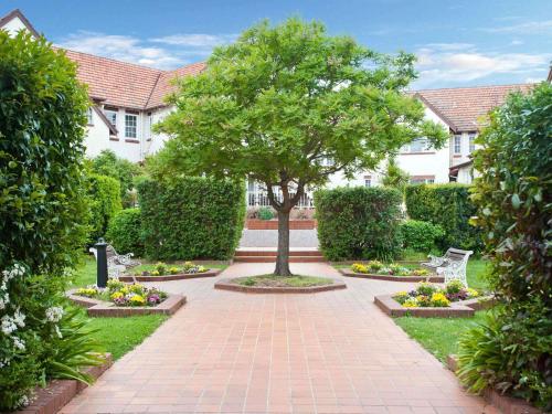 a tree in the middle of a brick walkway at Mercure Canberra in Canberra