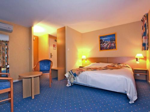 a hotel room with a bed and a table and chairs at Mercure Hexagone Luxeuil in Luxeuil-les-Bains