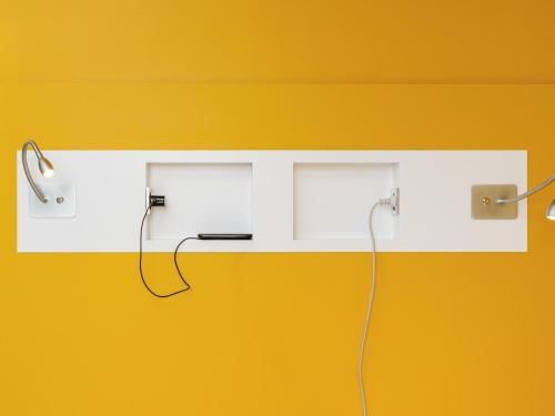 a white shelf with two ear phones on a yellow wall at ibis Budget Charleroi Airport in Charleroi
