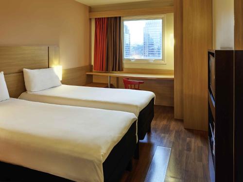a hotel room with two beds and a window at ibis Sao Paulo Morumbi in Sao Paulo