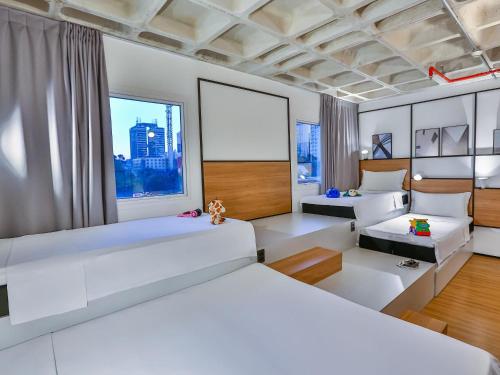 a bedroom with white beds and a large window at ibis Sao Paulo Morumbi in Sao Paulo