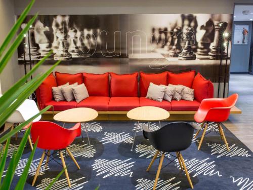 a red couch in a room with two tables and chairs at ibis Araçatuba in Araçatuba