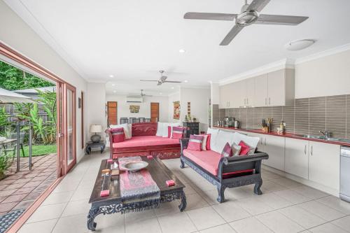 a living room with red furniture and a kitchen at Belle Escapes Villa Latania Palm Cove in Palm Cove