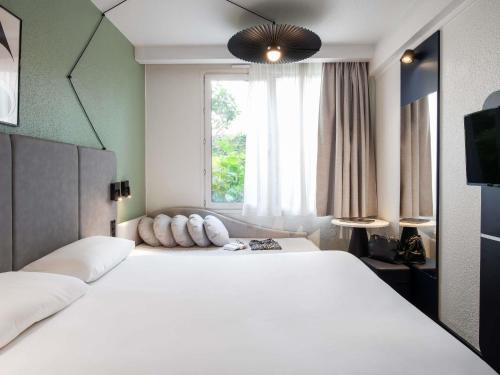 a bedroom with a large white bed with a window at ibis Paris Avenue d'Italie 13ème in Paris