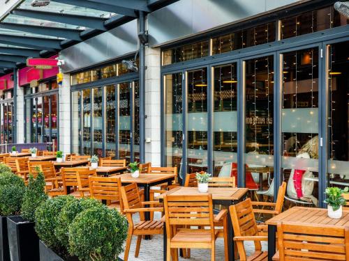 a restaurant with wooden tables and chairs in front of a building at ibis Bristol Centre in Bristol