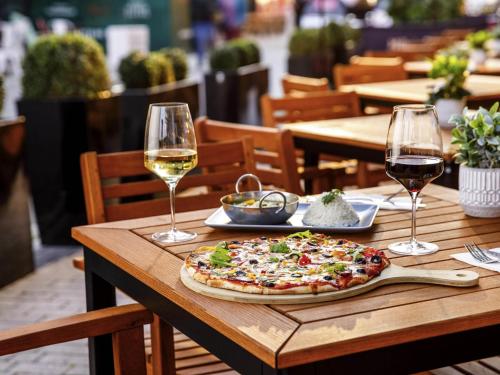 a pizza on a wooden table with two glasses of wine at ibis Bristol Centre in Bristol