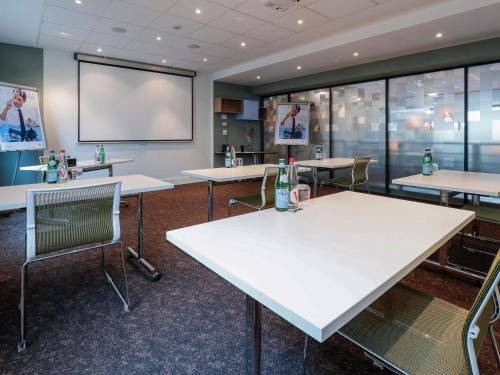a conference room with tables and a projection screen at Novotel Luxembourg Centre in Luxembourg