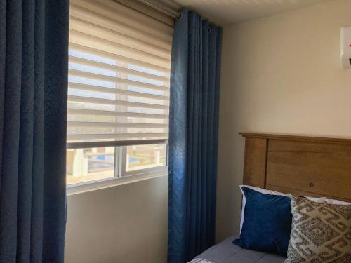 a bedroom with a window with a blue curtain at Casa Elegante con alberca a 5 min Aeropuerto y Consulado in Hermosillo