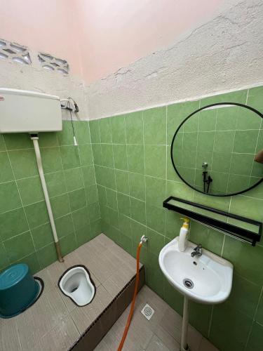 a green bathroom with a sink and a mirror at Teratak Tuan Homestay in Gua Sai