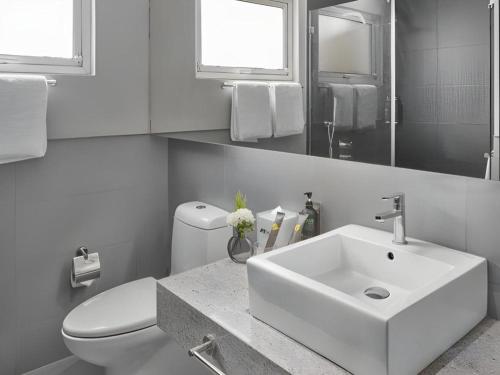 a white bathroom with a sink and a toilet at F1 Hotel Manila in Manila