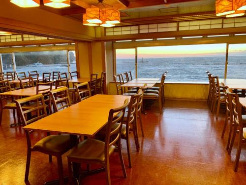 a restaurant with tables and chairs and a view of the ocean at Nishiizu Matsuzaki Itoen Hotel in Matsuzaki