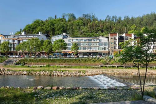 a water fountain in the middle of a river with buildings at 铂曼智慧酒店-张家界国家森林公园门票站店 in Zhangjiajie