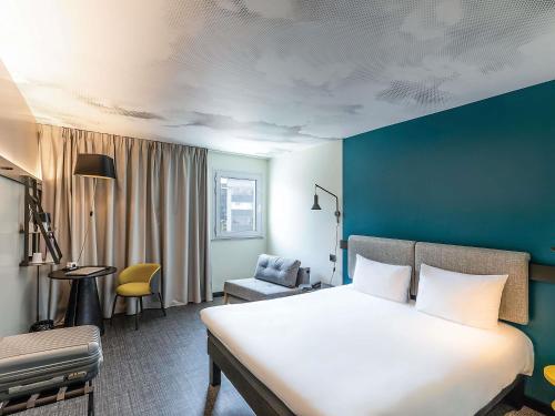 a bedroom with a large white bed and a blue wall at Ibis Malaga Centro Ciudad in Málaga