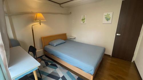 Dormitorio pequeño con cama, mesa y lámpara en Terminal in Takadanobaba, en Tokio