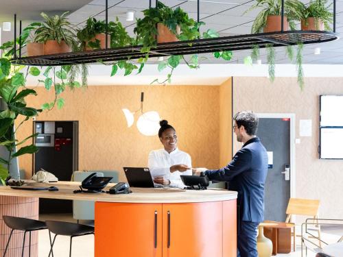 a man and a woman shaking hands in an office at Novotel Paris 13 Porte d'Italie in Le Kremlin-Bicêtre