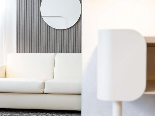 a white couch and a lamp in a living room at Novotel Paris 13 Porte d'Italie in Le Kremlin-Bicêtre