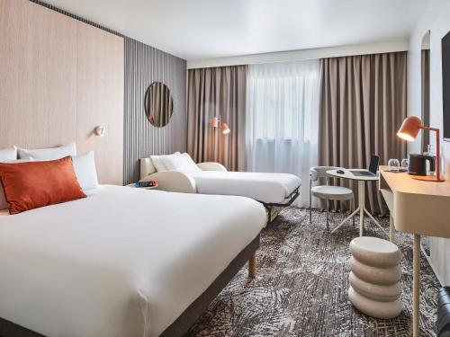 a hotel room with two beds and a desk at Novotel Paris 13 Porte d'Italie in Le Kremlin-Bicêtre