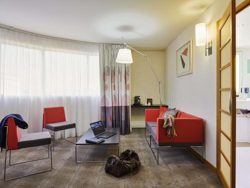 a living room with a couch and a laptop on a table at Novotel Paris 13 Porte d'Italie in Le Kremlin-Bicêtre