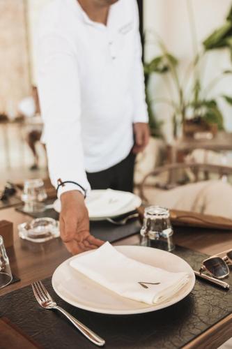 a person holding a plate on a table at Amarea Boutique Hotel in Dhërmi