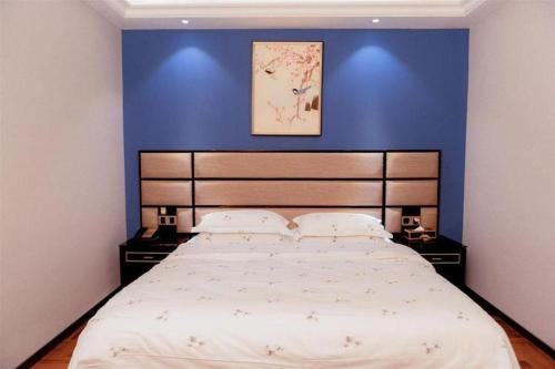 a bedroom with a large bed with a blue wall at Li An Hotel Shantou Xiashan Central Bus Station Branch in Shantou
