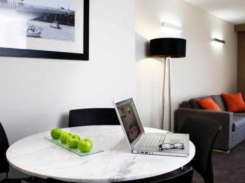 a white table with a laptop and green apples on it at Novotel Sydney International Airport in Sydney