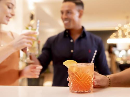 a man and a woman standing at a counter with a drink at Novotel Sydney International Airport in Sydney