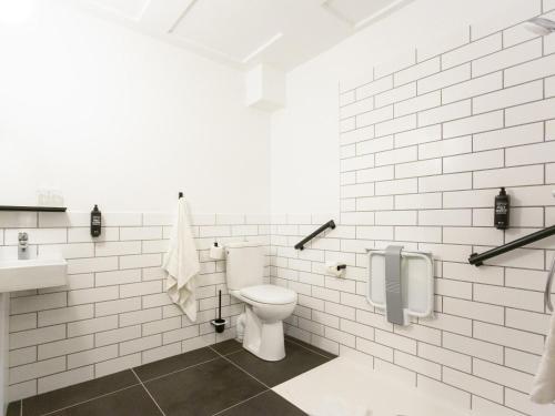 a white bathroom with a toilet and a sink at Ibis Centre Millau in Millau