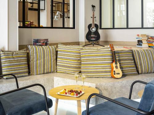 a living room with a couch with a table and a guitar at Ibis Centre Millau in Millau