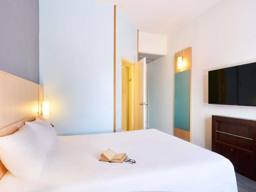 a bedroom with a white bed with a book on it at Ibis Como in Grandate
