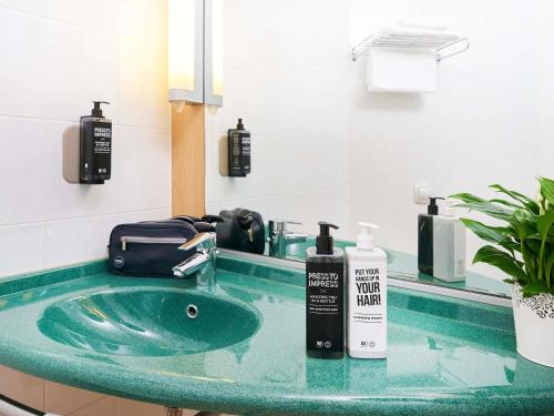 a bathroom with a green sink and a mirror at Ibis Como in Grandate
