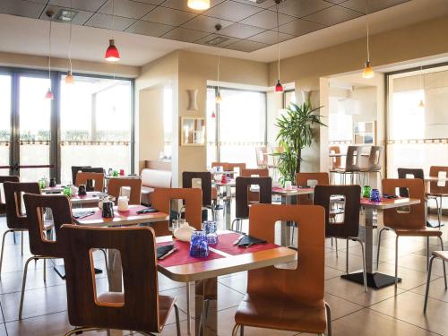 a dining room with tables and chairs and windows at Ibis Como in Grandate