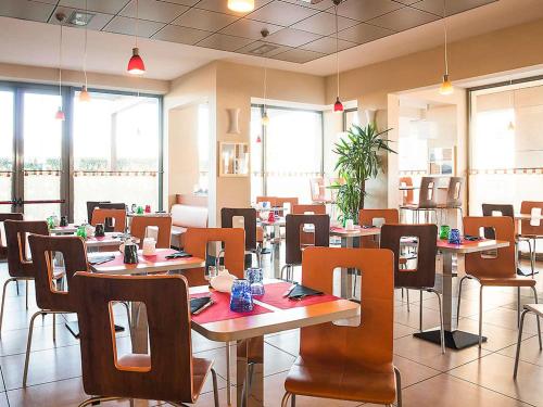 a dining room with tables and chairs and windows at Ibis Como in Grandate
