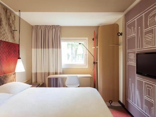 a bedroom with a white bed and a window at Ibis Aéroport Bâle Mulhouse in Saint-Louis