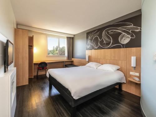 a hotel room with a bed and a tv at ibis Issoire in Issoire