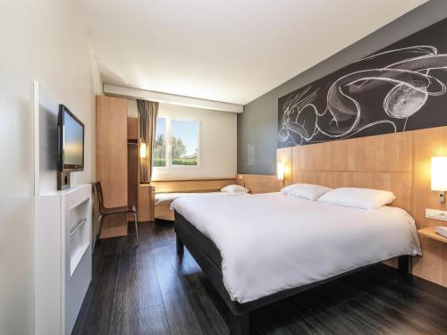 a hotel room with a large bed and a tv at ibis Issoire in Issoire