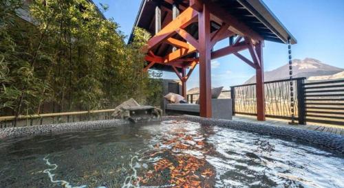 a pool of water with a wooden gazebo at Yufuin Luxury Villa -zakuro- in Yufuin