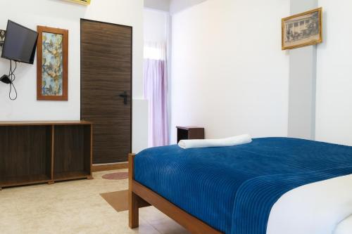 una camera da letto con un letto blu e una televisione di CTC Receptions a Anuradhapura