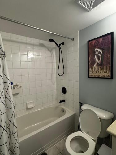 a bathroom with a tub and a toilet and a poster at DT Townhome 1BR steps to transit in Toronto