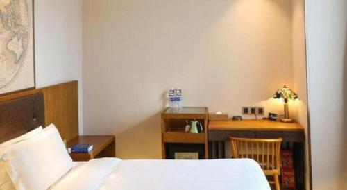 a bedroom with a bed and a desk with a desk at James Joyce Coffetel Changchun People's Square in Changchun