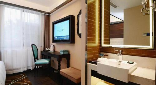 a bathroom with a sink and a desk and a television at Xana Hotelle Xi'an Zhonglou, Huimin Street Metro Station in Xi'an