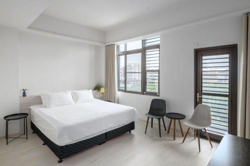 安平区にある樸寓國際青年旅舍の白いベッドルーム(ベッド1台、椅子2脚付)