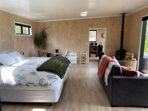 a bedroom with a large bed and a couch at Whakaipo Bay Cabin Retreat Taupo in Taupo