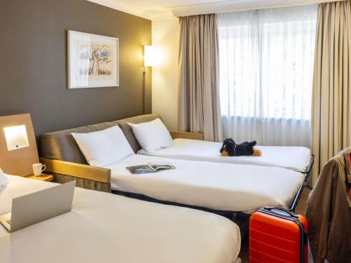 a hotel room with two beds and a dog sitting on the bed at Novotel Bristol Centre in Bristol