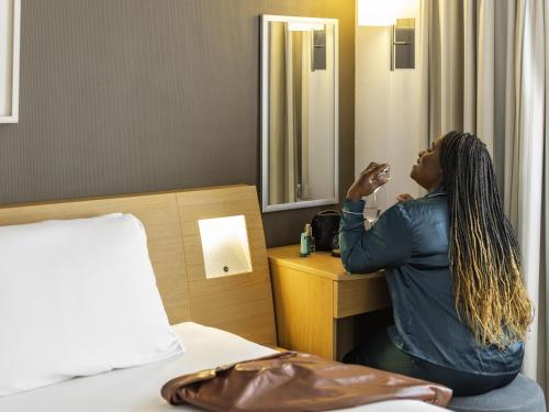 a woman in a hotel room looking in a mirror at Novotel Bristol Centre in Bristol