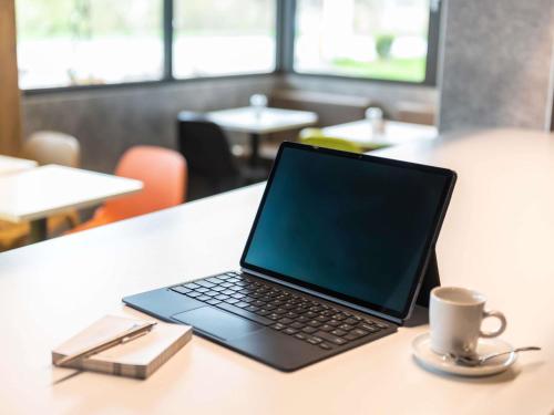 a laptop computer sitting on a table with a cup of coffee at ibis budget Muenchen Ost Messe in Aschheim
