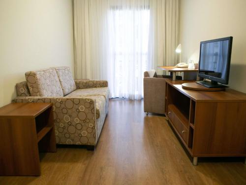 a living room with a couch and a flat screen tv at Mercure Sao Caetano do Sul in São Caetano do Sul