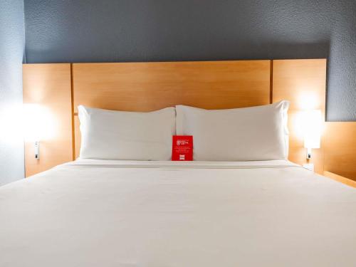 a bed with two white pillows and a red box on it at ibis Joinville in Joinville