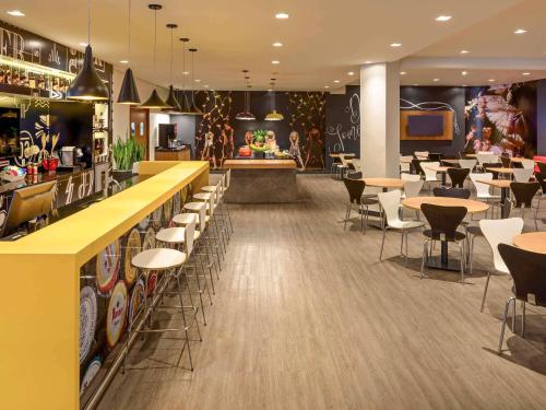 a restaurant with tables and chairs and a bar at ibis Joinville in Joinville