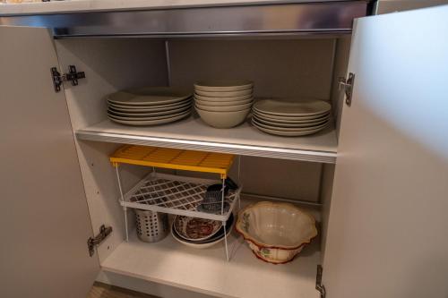 a cupboard with plates and dishes in it at New 2BR Suite With Great Ocean View in West Vancouver in West Vancouver